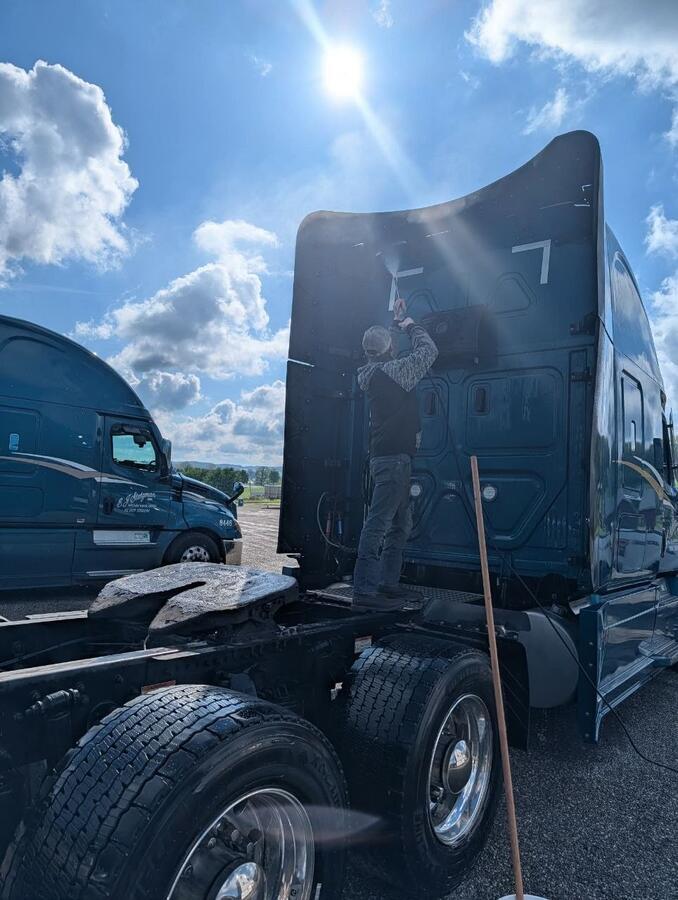 Worker pressure washing the truck — showing the real work